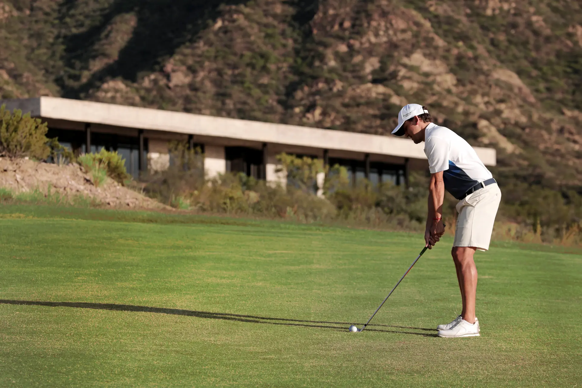 una persona jugando al golf con el edificio Mendoza Norte al fondo